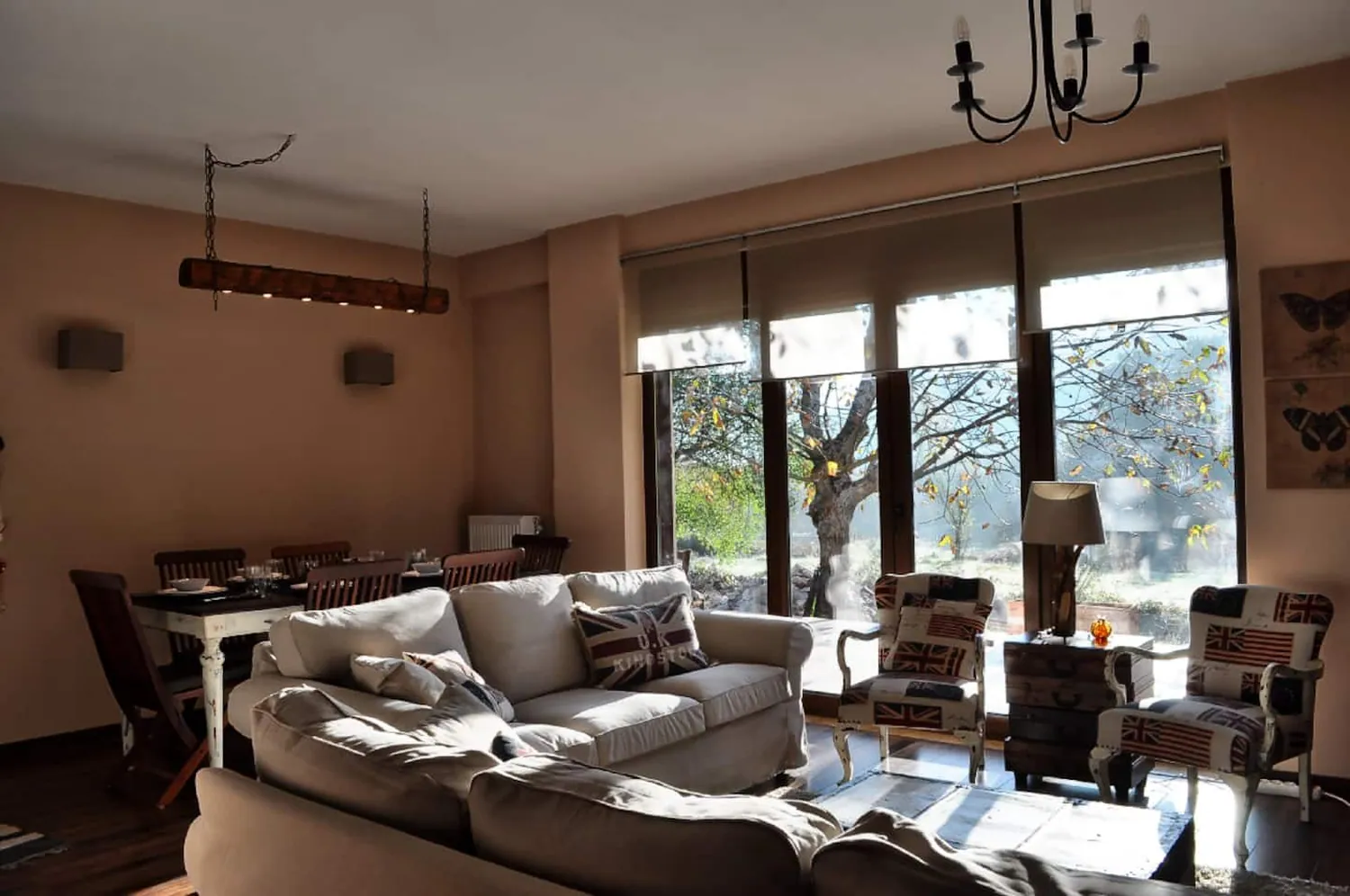 Σαλόνι με λευκούς καναπέδες, τραπεζαρία και μεγάλα τζάμια προς τον κήπο